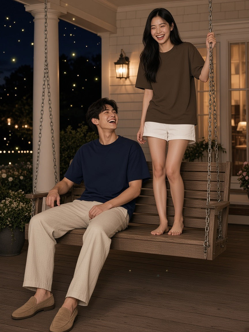 Two people in the Marcel Afters Heavyweight Drop Shoulder Cotton T-Shirt in Navy and Coffee on a Hamptons porch swing at night