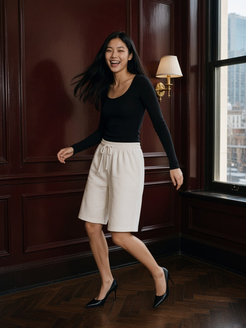 Woman in the Heavyweight Fleece Loose Fit Shorts in Lucent White in a hotel suite on the Upper East Side, New York by day