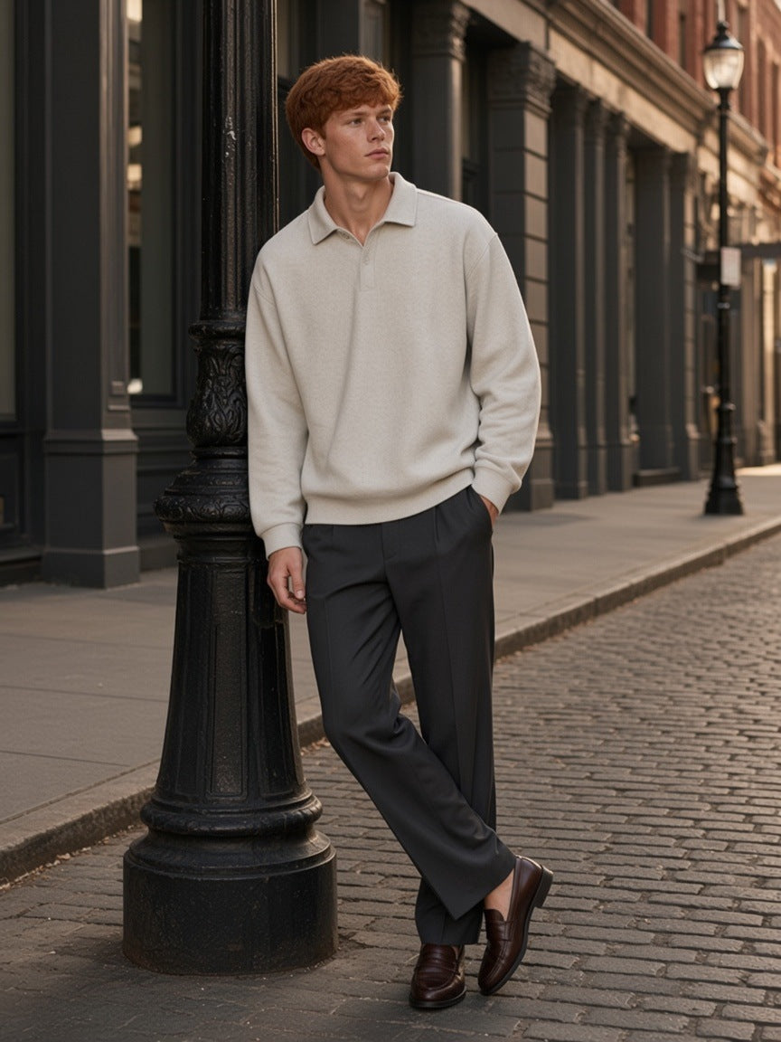 Man in the Heavyweight Fleece Polo Sweatshirt in Oat Gray with charcoal trousers and loafers, walking a SoHo street in New York by day