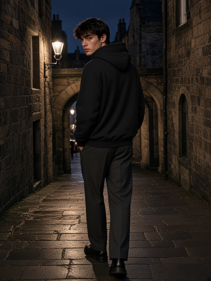 Man in the Marcel Afters Heavyweight Hidden Pocket Fleece Hoodie in Black in an Edinburgh Old Town close at night