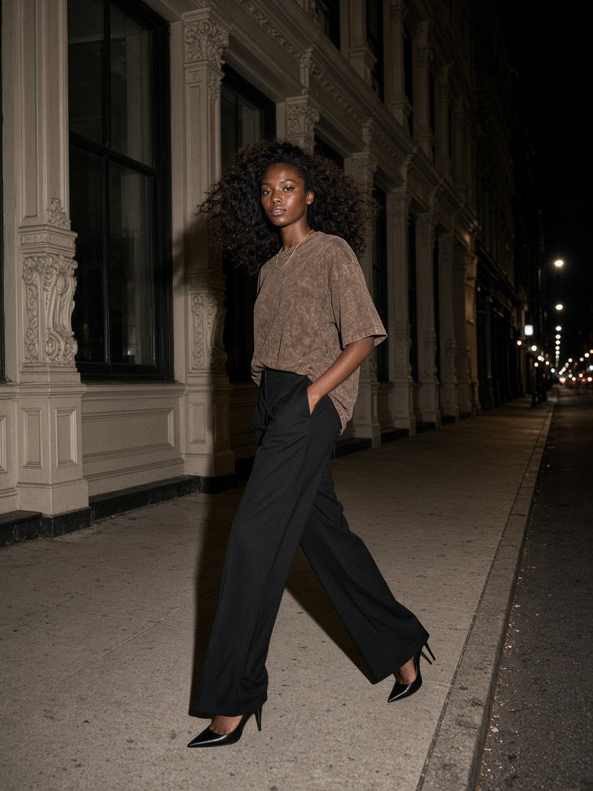 Woman in the Marcel Afters Women's Heavyweight Mineral Wash Boxy T-Shirt in Brown running along a cast-iron street in SoHo, New York at night