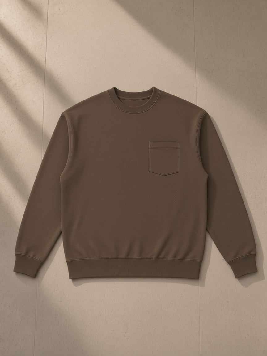 Heavyweight patch pocket crewneck sweatshirt in Coffee, laid flat on pale limestone, front view