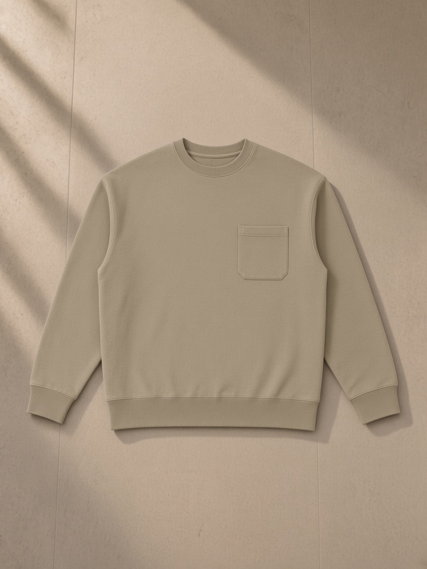 Heavyweight patch pocket crewneck sweatshirt in Khaki, laid flat on pale limestone, front view