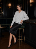 Woman in a Flower Gray heavyweight polo-collar sweatshirt and black satin skirt on a bar stool in a panelled lounge