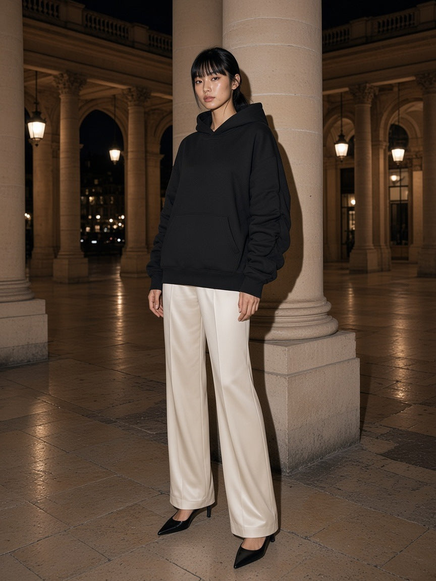 Woman in the Marcel Afters heavyweight ruched sleeves hoodie in Black standing in the Palais-Royal colonnade in Paris at night
