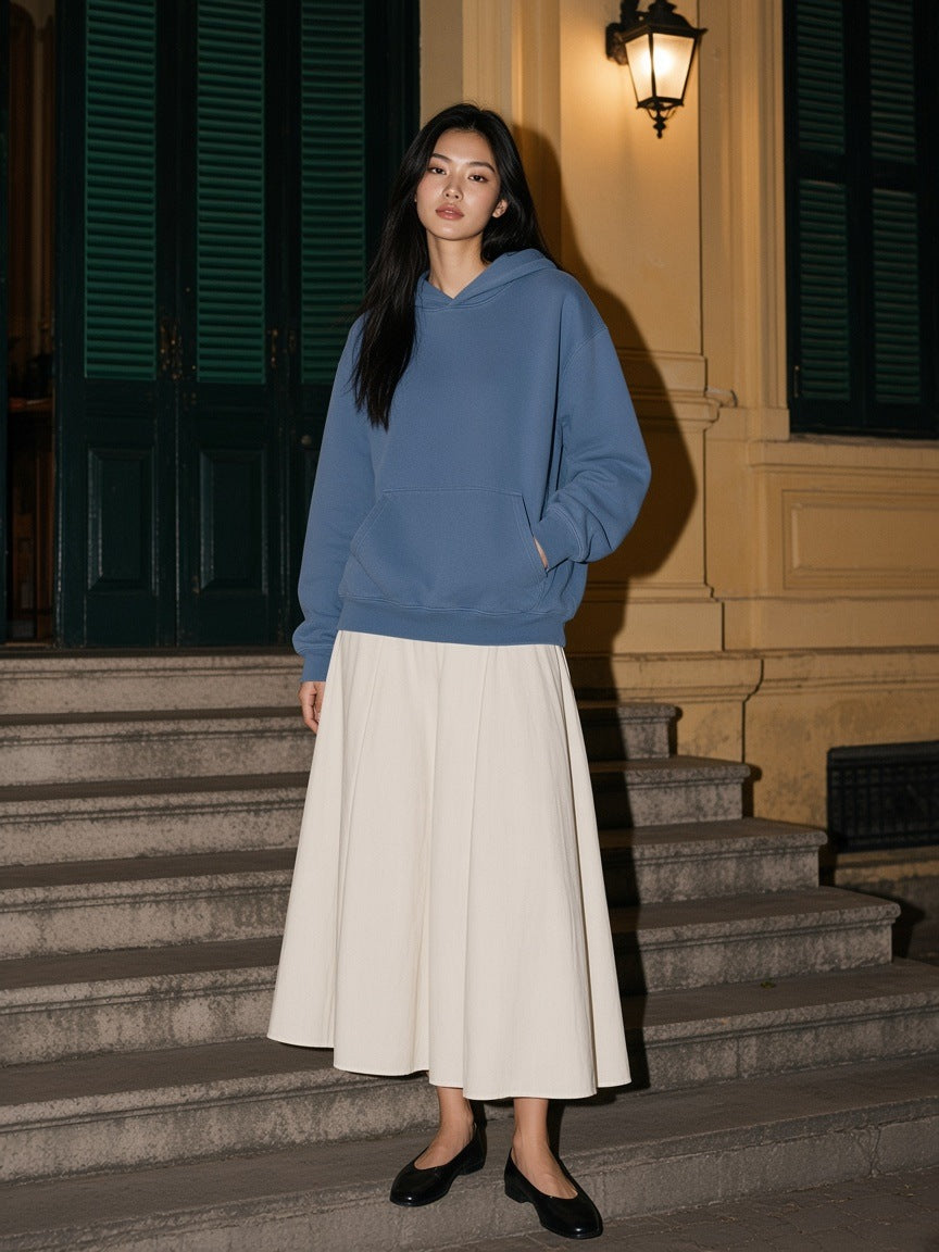 Woman in the heavyweight vintage wash boxy hoodie in Washed Blue standing on the steps of a colonial villa in Hanoi at night