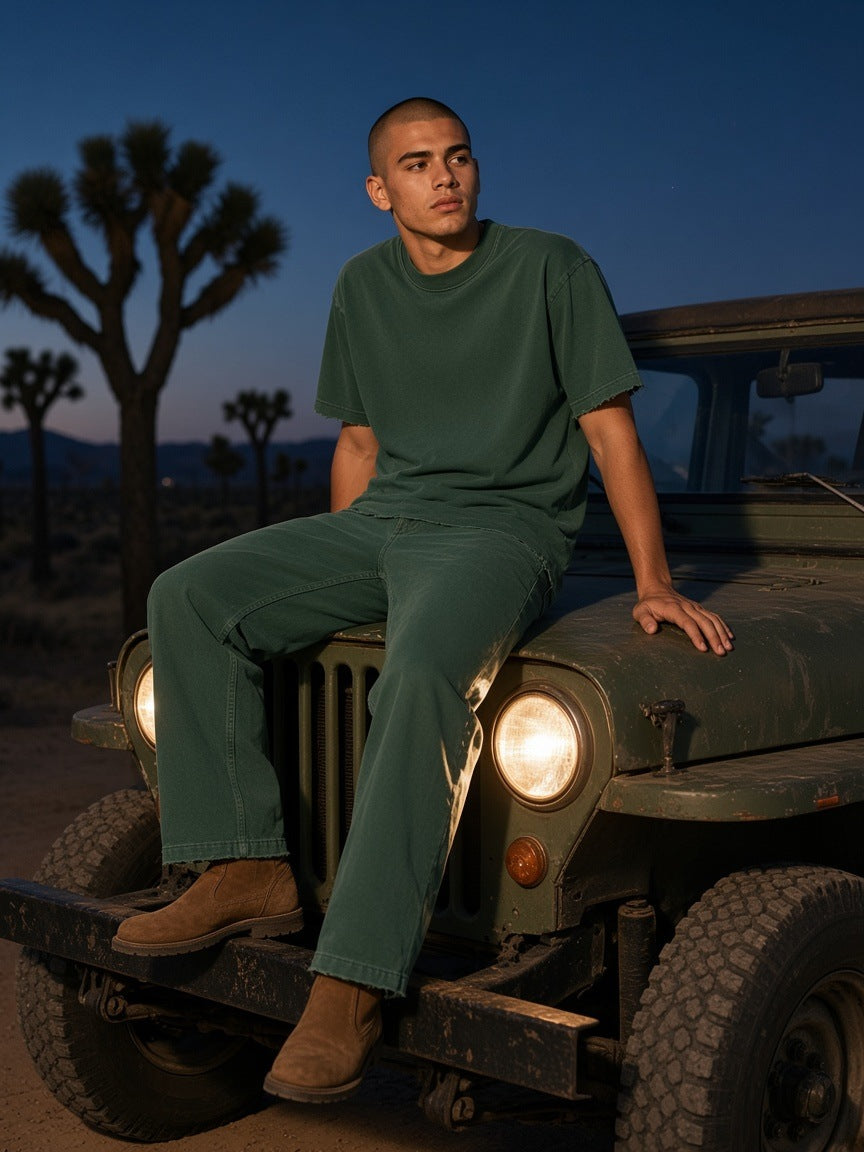 Man in the Heavyweight Vintage Washed Frayed T-Shirt in Retro Green seated on a jeep near Joshua Tree at dusk