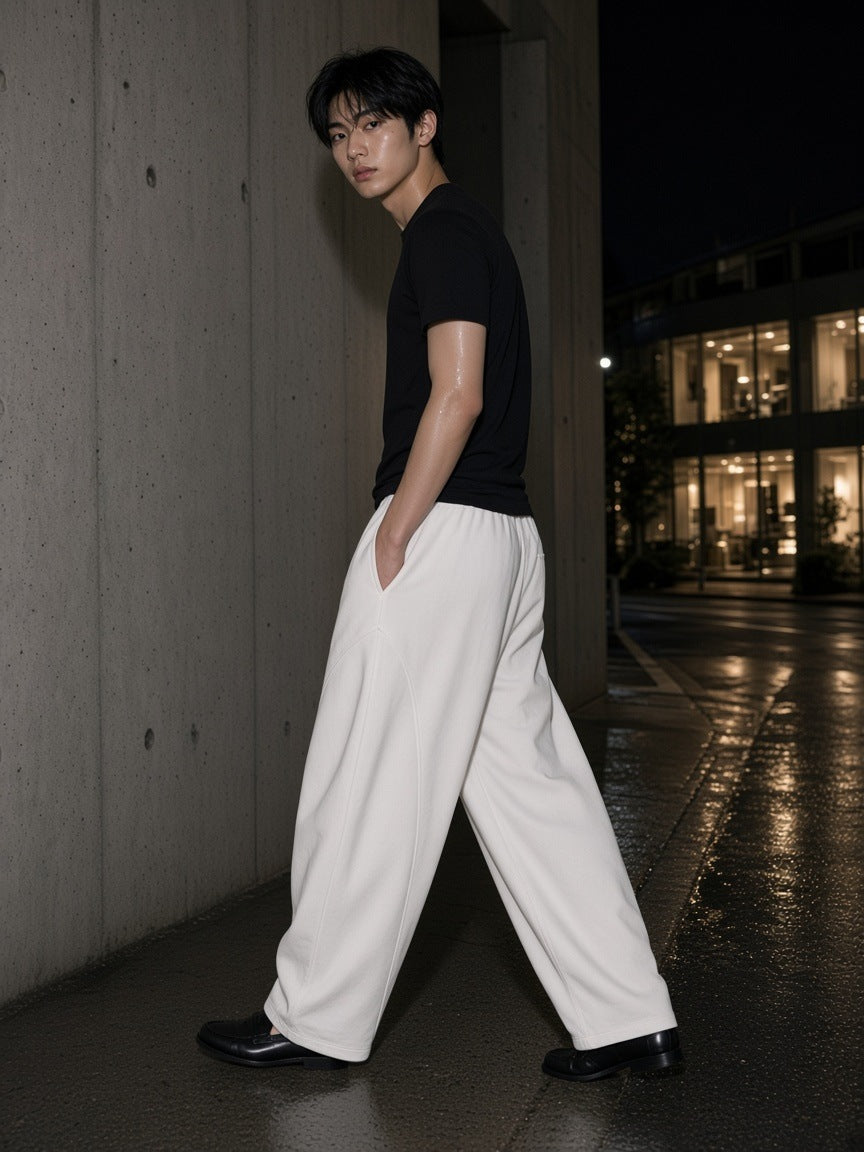 Man in the Heavyweight Wide Leg Panel Sweatpants in White walking a wet concrete street in Aoyama, Tokyo at night