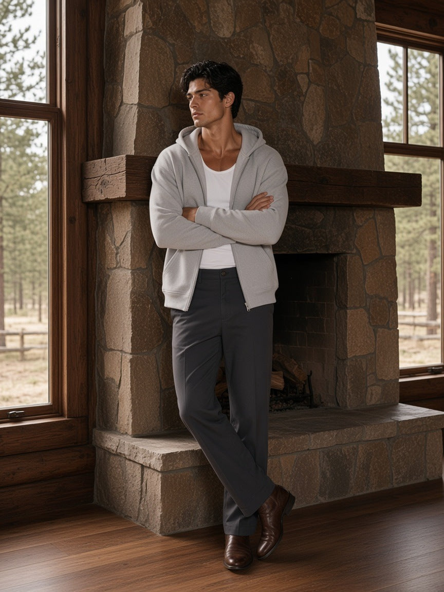 Man in the Heavyweight Zip-up Hoodie in Flower Gray worn open over a white tank, by a stone fireplace at a ranch lodge in Wyoming in the morning