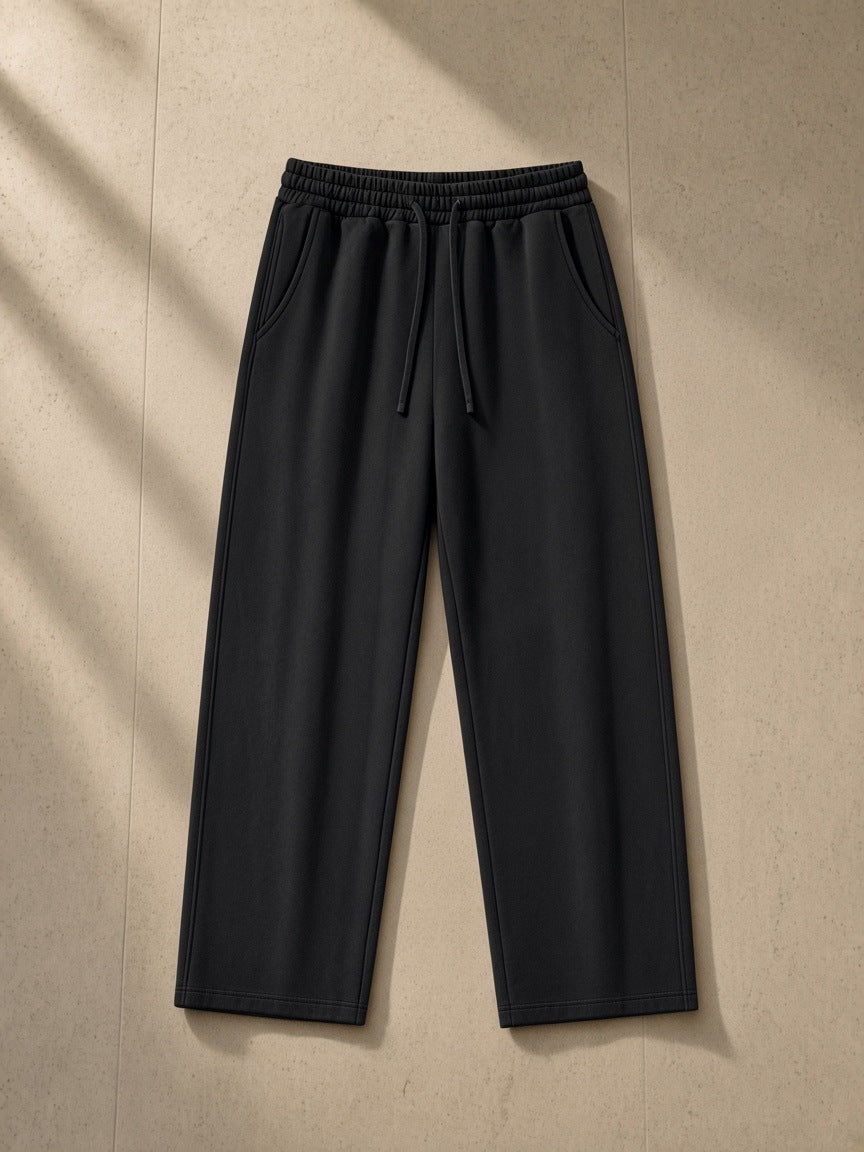 Heavyweight vintage wash sweatpants in Black, laid flat on pale limestone