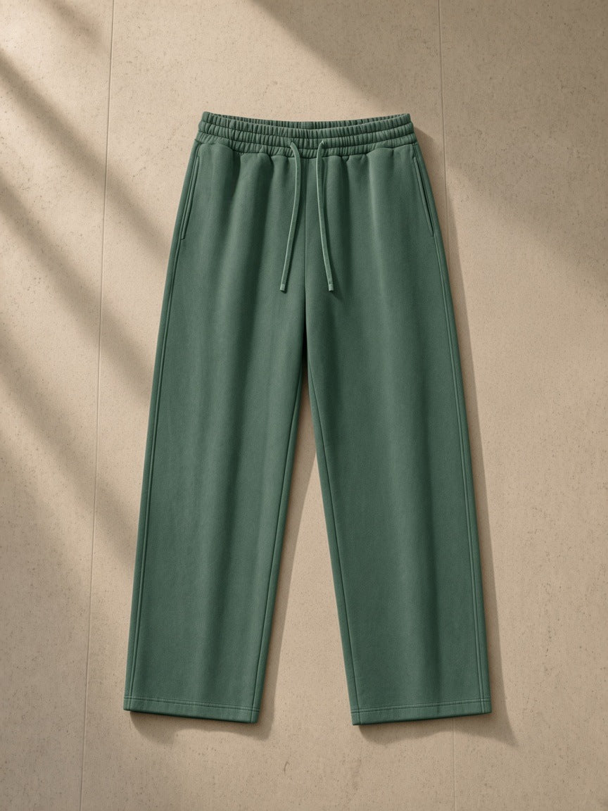 Heavyweight vintage wash sweatpants in Blackish Green, laid flat on pale limestone