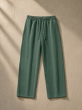 Heavyweight vintage wash sweatpants in Blackish Green, laid flat on pale limestone