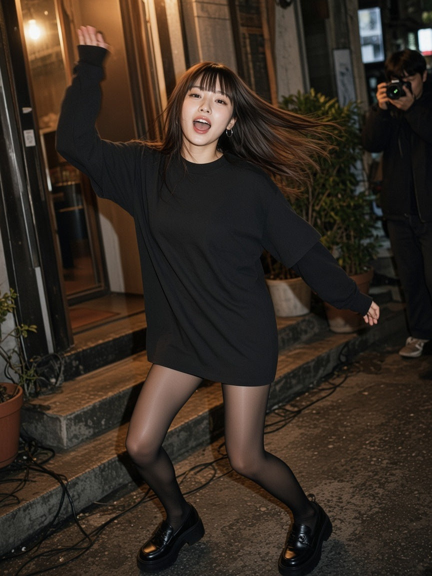 Woman in the Layered Oversized T-Shirt in Black worn as a dress with sheer tights and platform loafers, dancing on the steps of a Shibuya bar at 1am