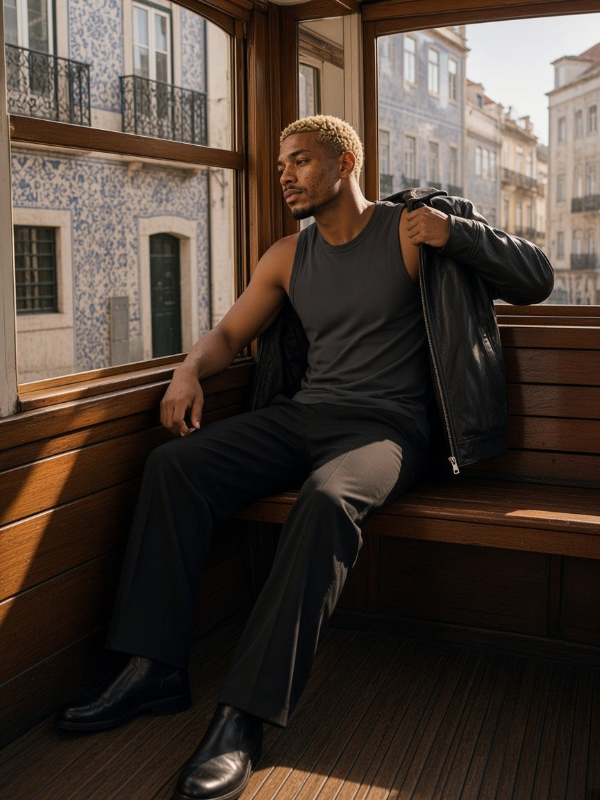 Man in the Sorona Quick-Dry Cooling Tank Top in Dark Gray with a leather jacket and black trousers, by the window of a Lisbon tram in the morning