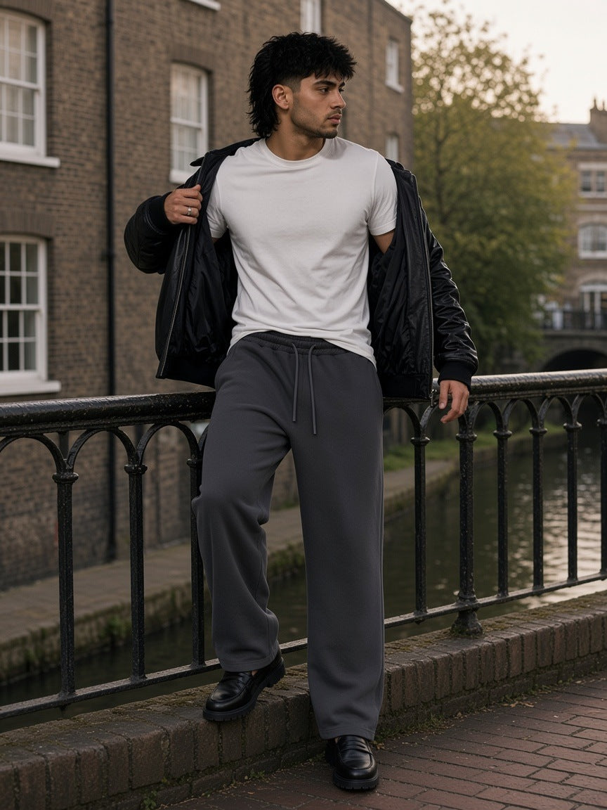 Man in the Snow Washed Raw Edge Sweatpants in Dark Gray with a white tee and leather jacket, on a footbridge over Regent's Canal, London in the morning