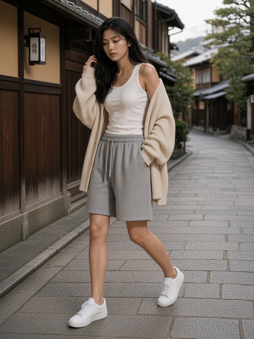Woman in the Essential Heavyweight Fleece Shorts in Flower Gray with a white tank, oatmeal cardigan and white sneakers, walking a stone lane in Higashiyama, Kyoto in the morning