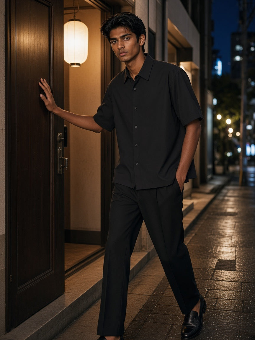 Man in the Lightweight Cotton Short Sleeve Shirt in Black, pushing open a hotel bar door on a Tokyo side street at night