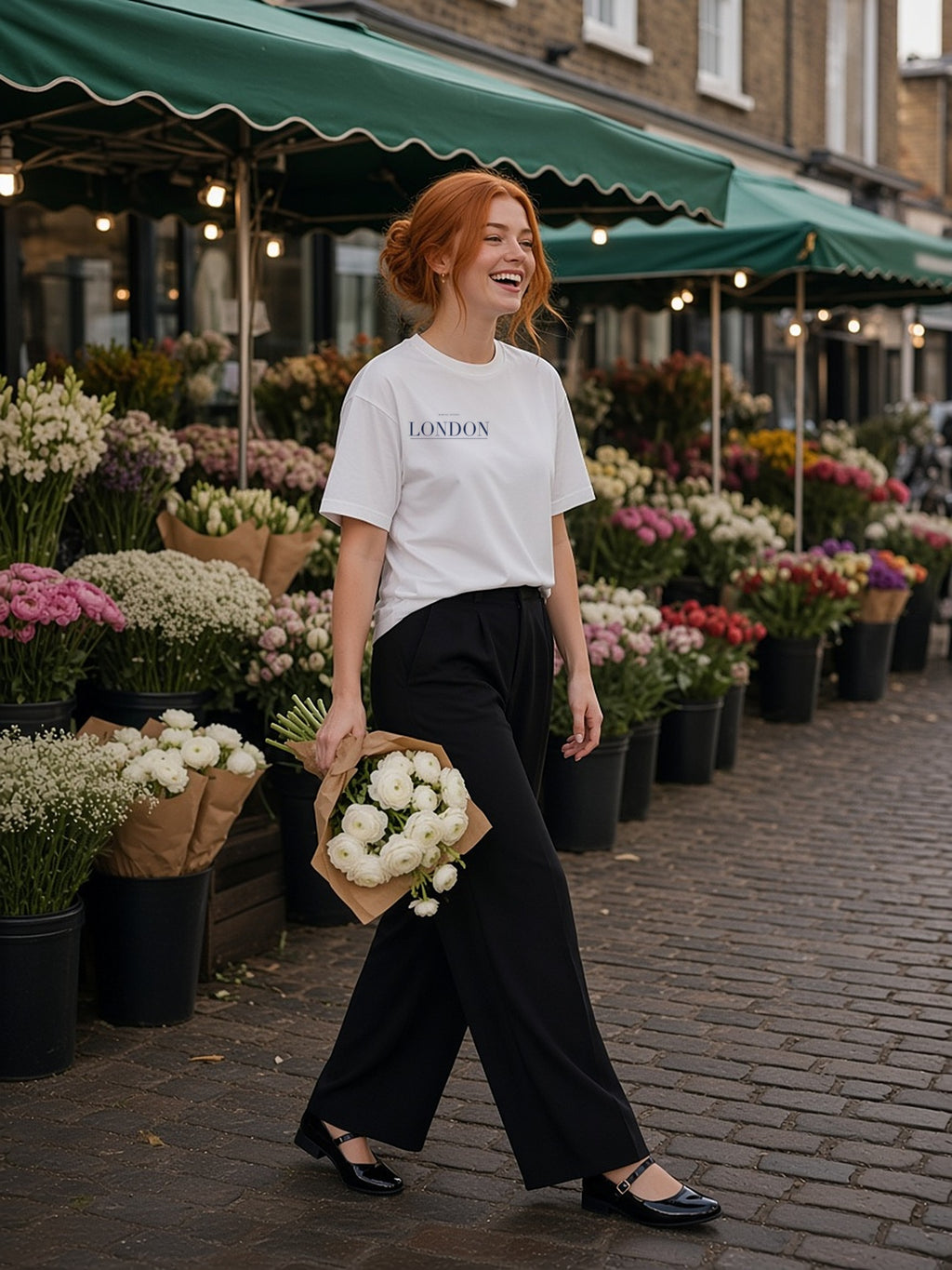 Woman in the London tee in White at the Columbia Road flower market on a Sunday morning, holding ranunculus