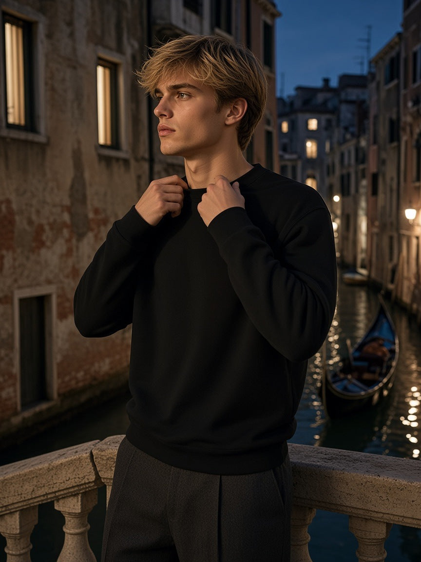 Man in the Marcel Afters Loose Crewneck Sweatshirt in Black on a canal bridge in Venice at night