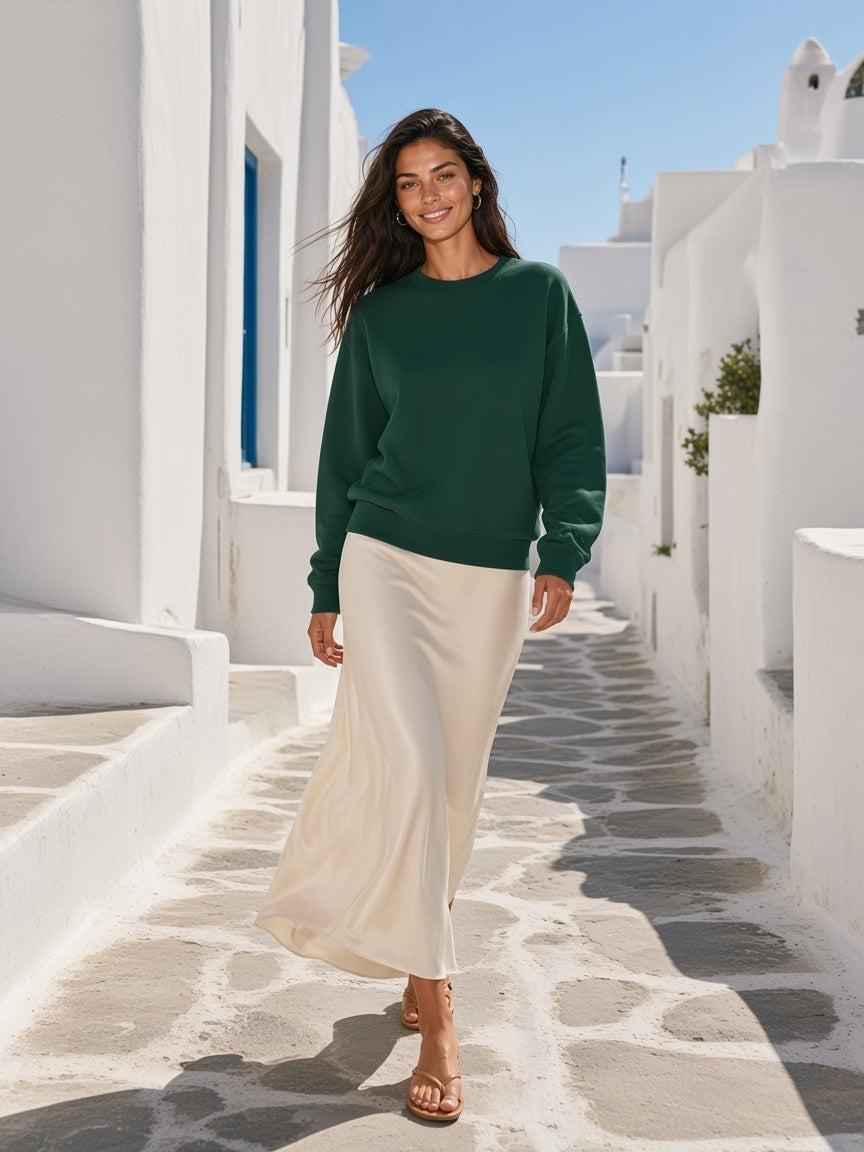 Woman in the loose crewneck sweatshirt in Dark Green standing on a whitewashed stair on Mykonos in the morning