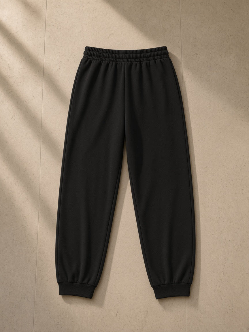 Women's Loose Fit Tapered Joggers in Black, laid flat on pale limestone, back view