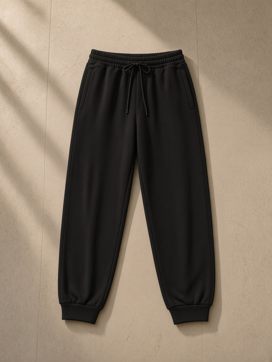 Women's Loose Fit Tapered Joggers in Black, laid flat on pale limestone