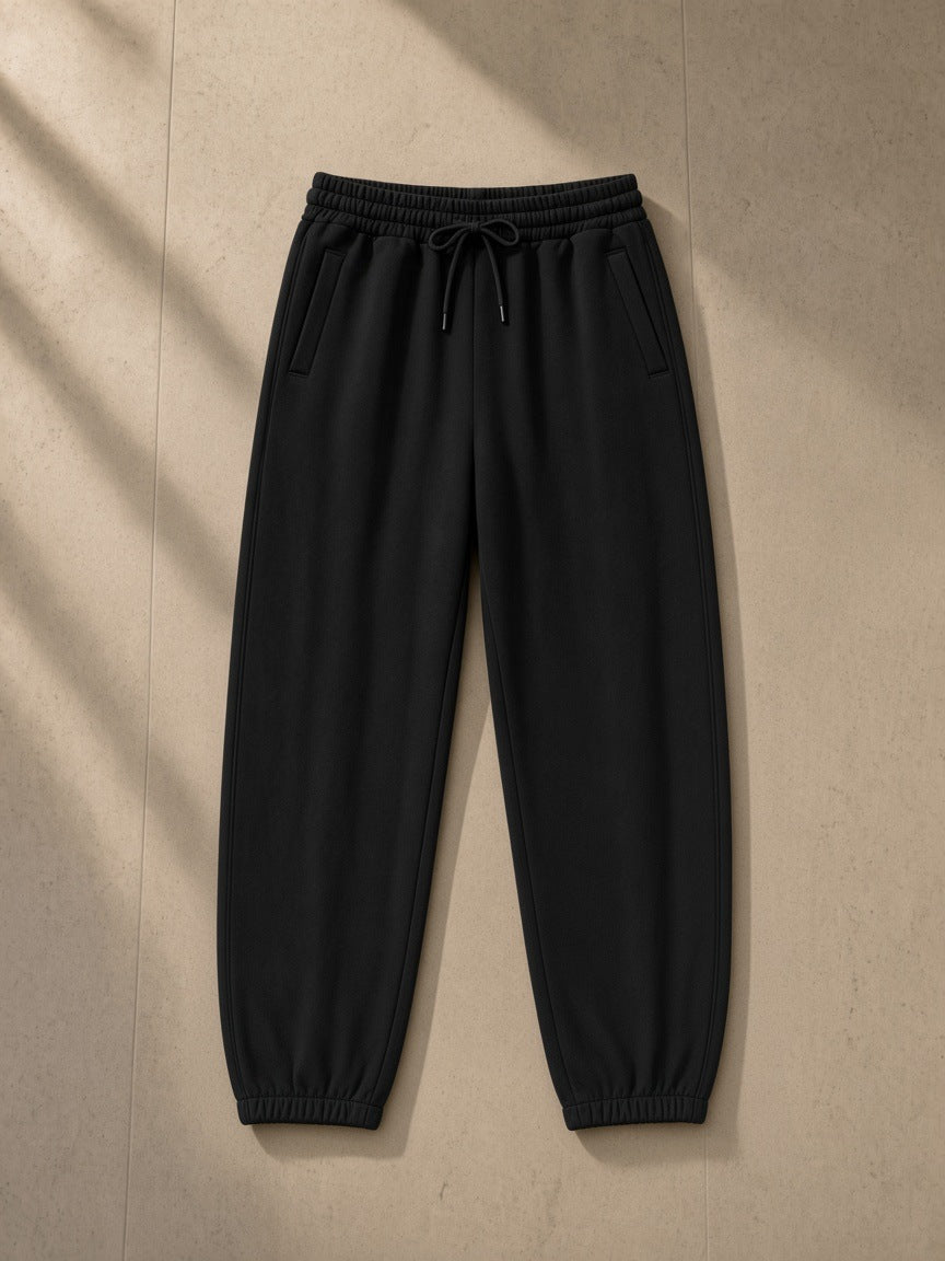 Loose Fit Tapered Joggers in Black, laid flat on pale limestone, tapered leg with elastic ankle cuffs