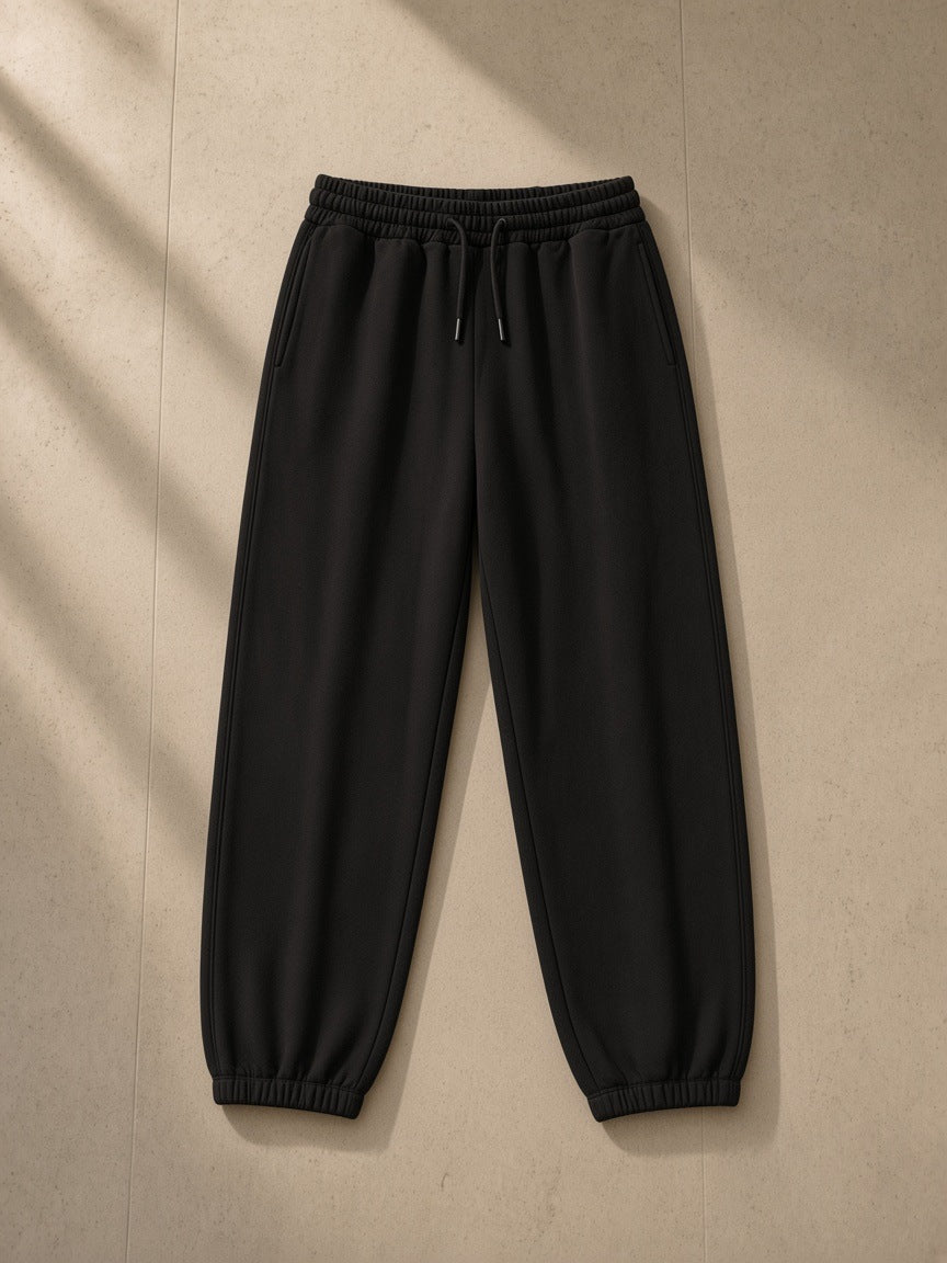 Men's Loose Fit Tapered Joggers in Black, laid flat on pale limestone