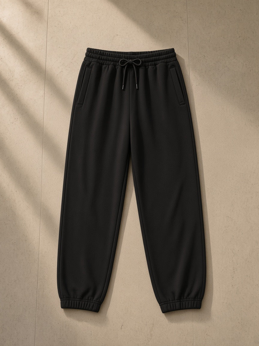Women's Loose Fit Tapered Joggers in Black, laid flat on pale limestone