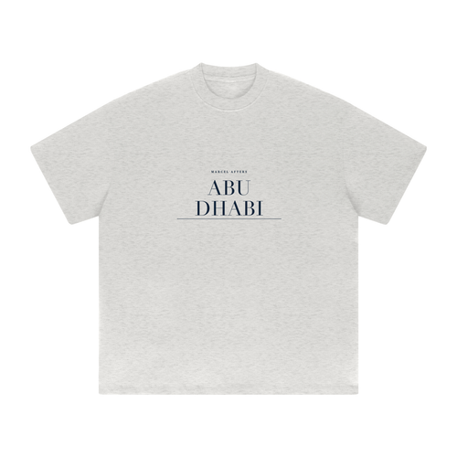 Abu Dhabi heavyweight tee in Oat Gray, front view with the Abu Dhabi name engraved as a navy plate across the chest. Marcel Afters.