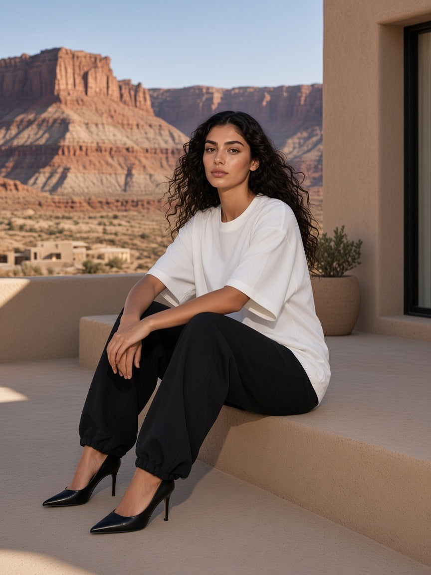 Woman in the Boxy Oversized T-Shirt in White sitting on a step in a desert resort courtyard in Utah in the morning
