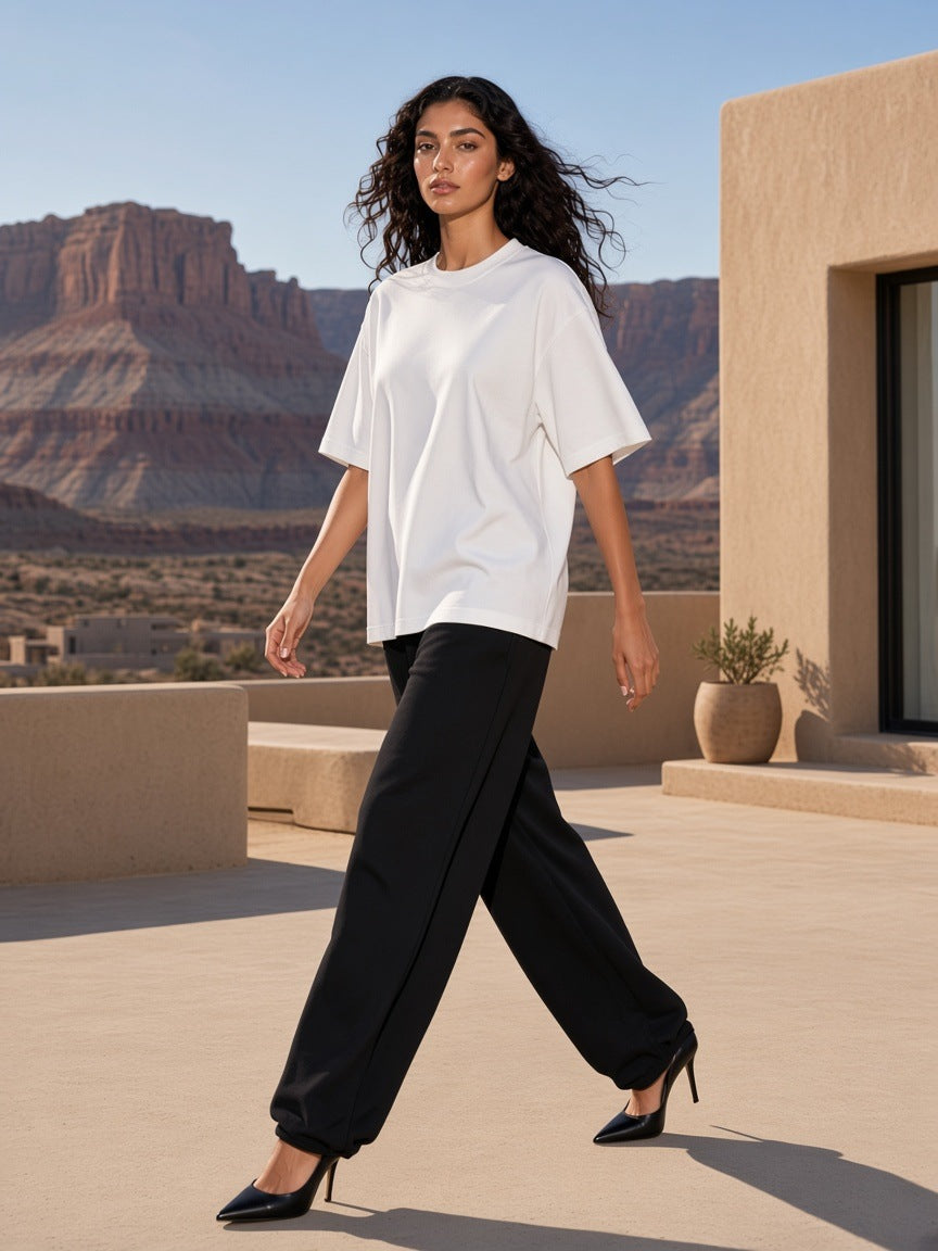 Marcel Afters Boxy Oversized T-Shirt in White, worn by a woman, walking in a desert courtyard