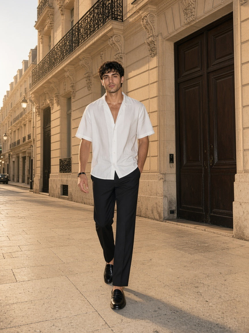 Marcel Afters Boxy Short Sleeve Shirt in White, worn by a man, walking a sunlit stone street in a white shirt and black trousers