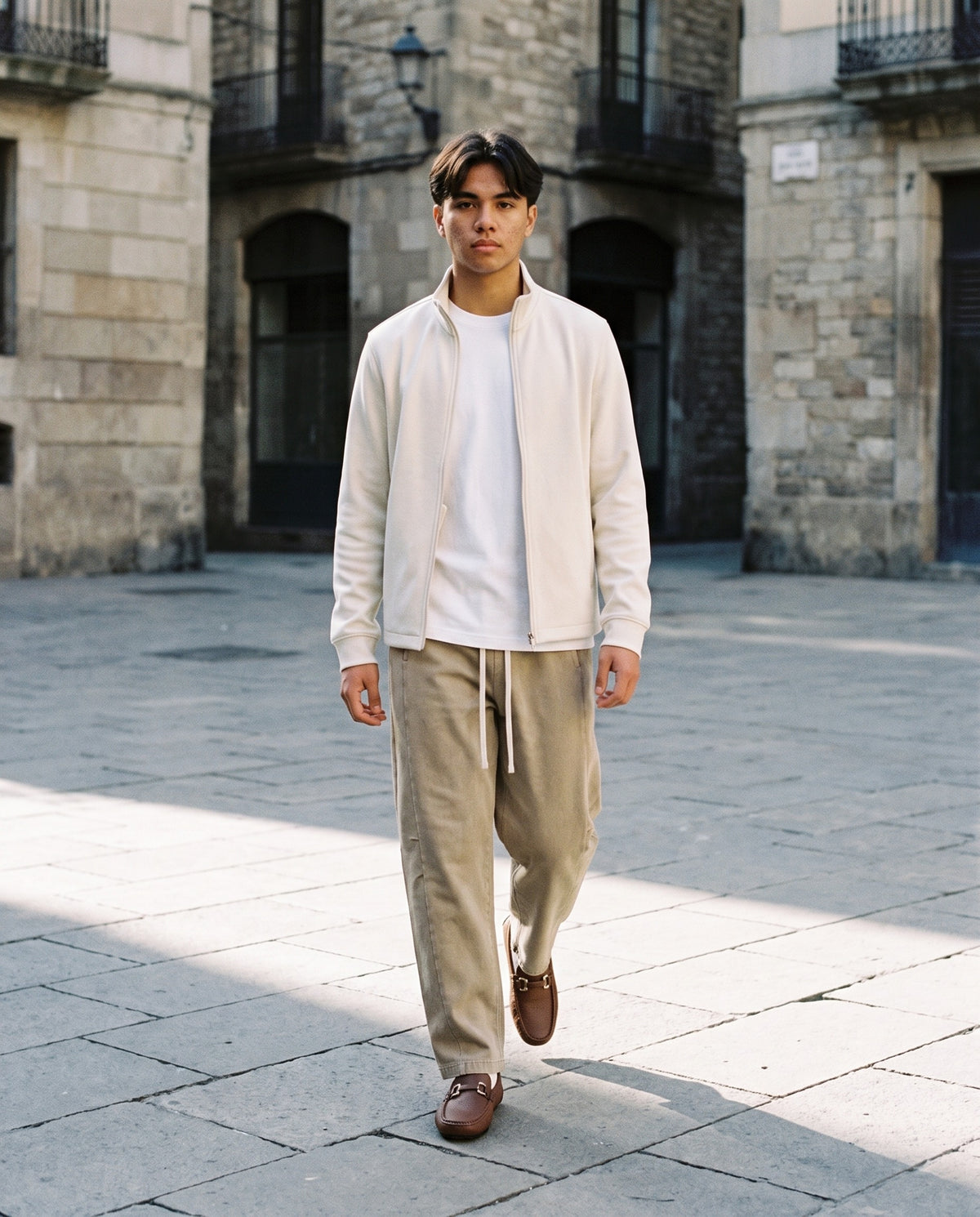 Man wearing The Grand Tour Loafer with the Heavyweight Long Sleeve T-Shirt in White, Mineral Wash Barrel Leg Pants in Khaki, Stand Collar Jacket in Beige. The Long Lunch, Autumn–Winter 2026 campaign