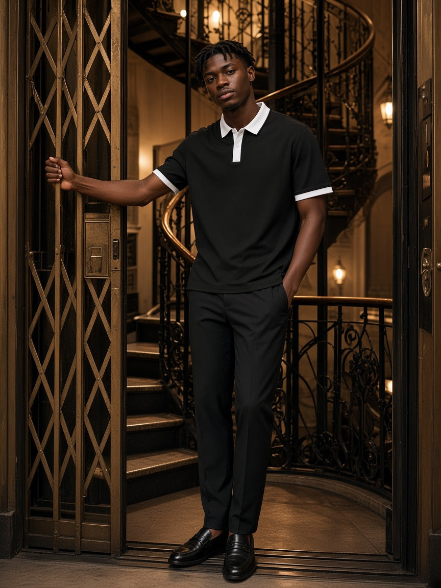 Marcel Afters Color Block Polo Shirt, 240 gsm in Black with White, worn by a man, standing by a wrought-iron staircase in a black polo with white trim