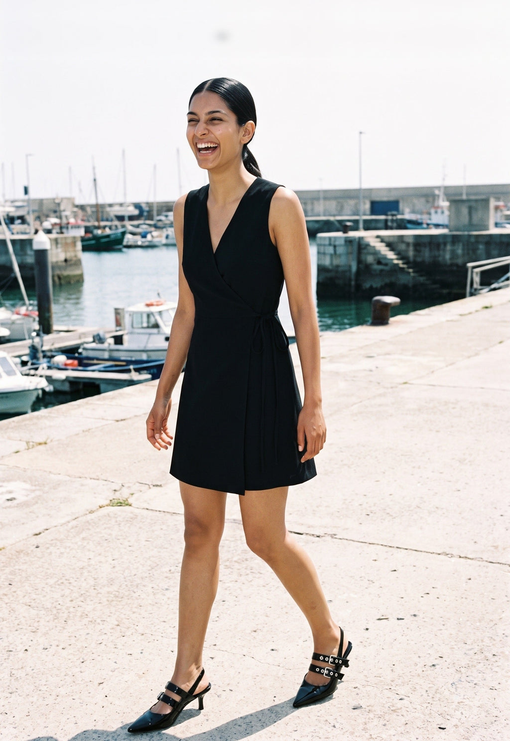 Woman wearing The Do Not Disturb Slingback in Black with black sleeveless short A-line dress with a wrap front and round neck, flash photograph