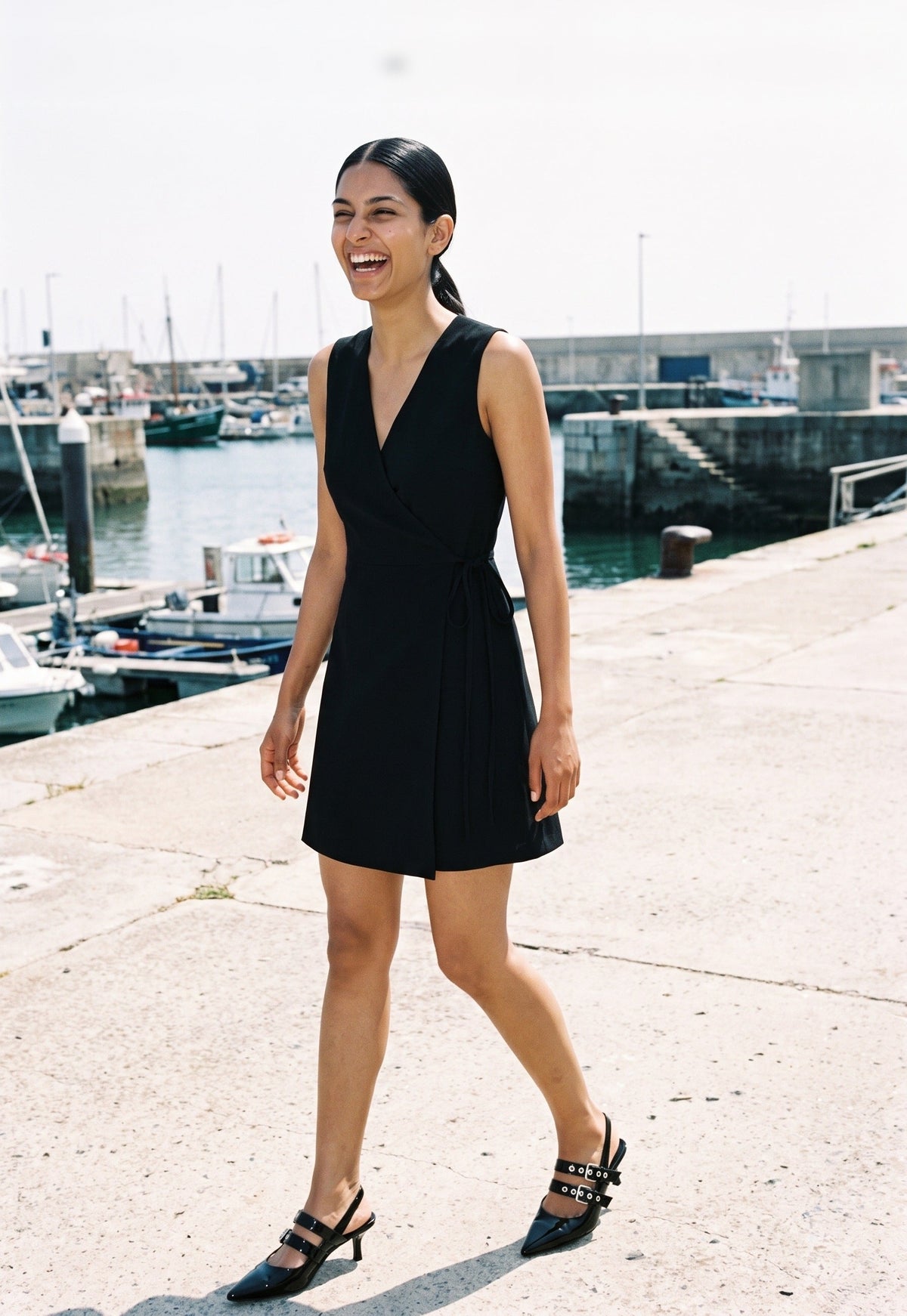 Woman wearing The Do Not Disturb Slingback in Black with black sleeveless short A-line dress with a wrap front and round neck, flash photograph