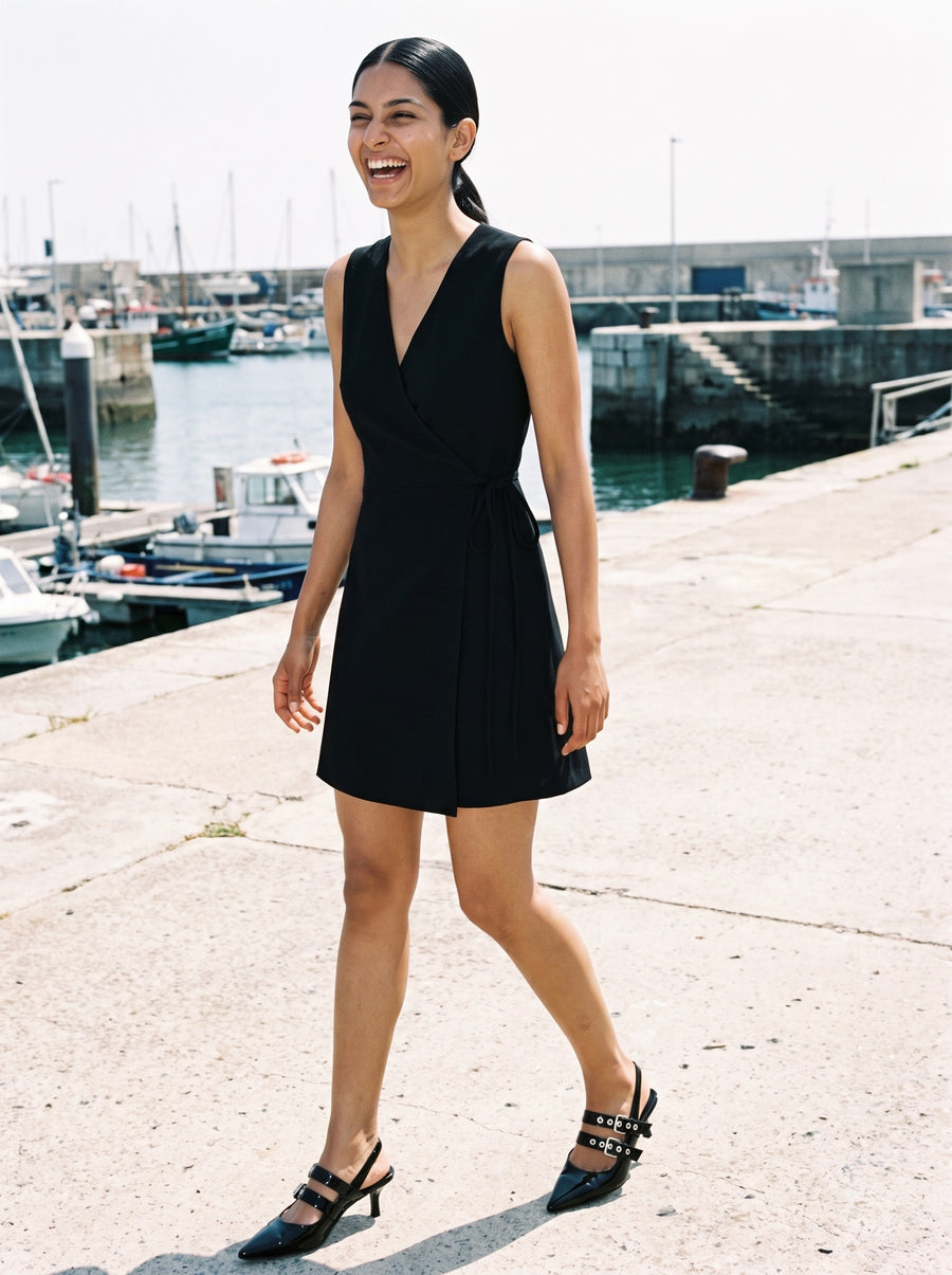 Woman wearing The Do Not Disturb Slingback in Black with black sleeveless short A-line dress with a wrap front and round neck, flash photograph