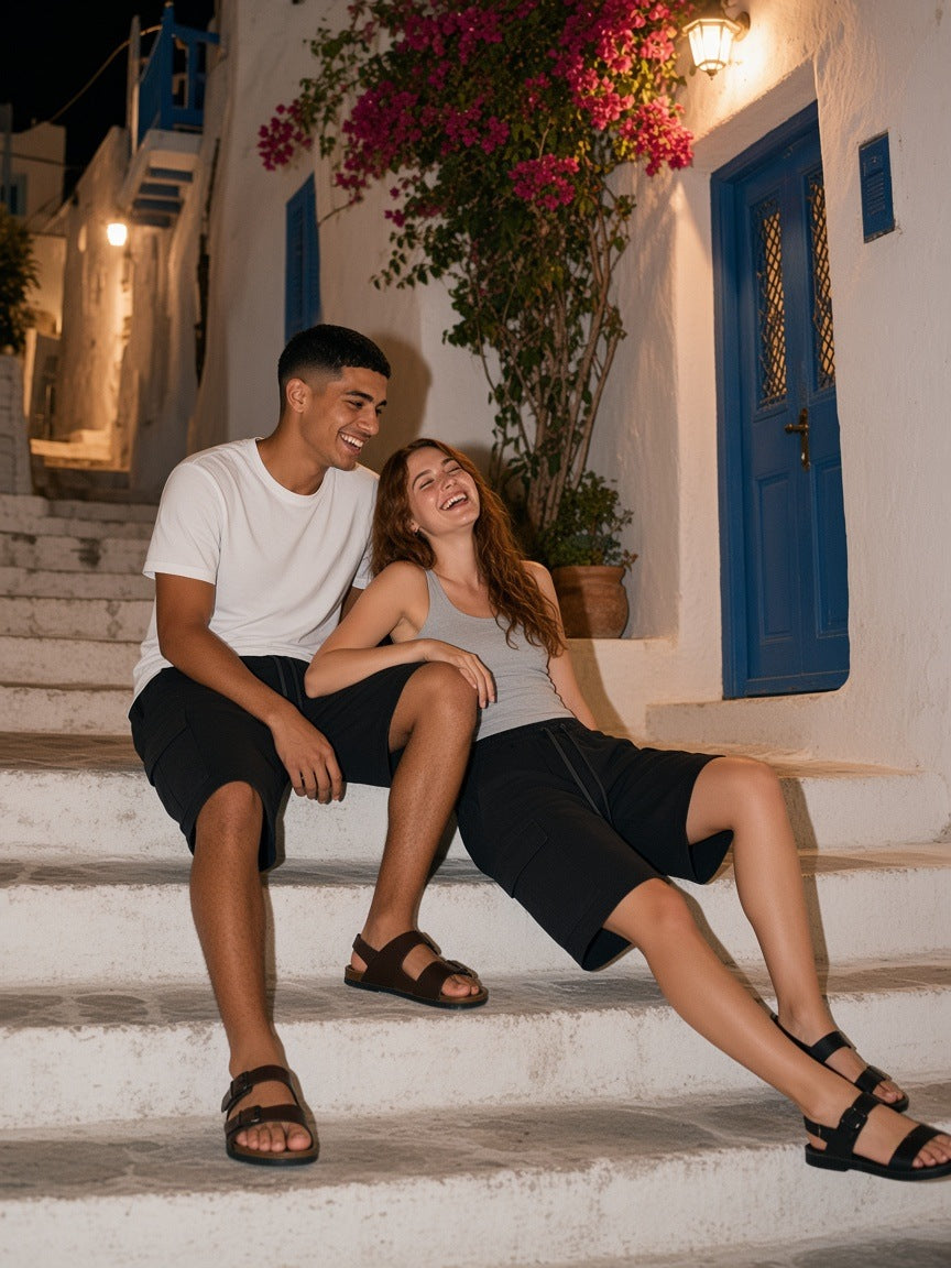 Marcel Afters Drawstring Cargo Shorts in Black, worn by a man and a woman, laughing together on whitewashed steps under bougainvillea
