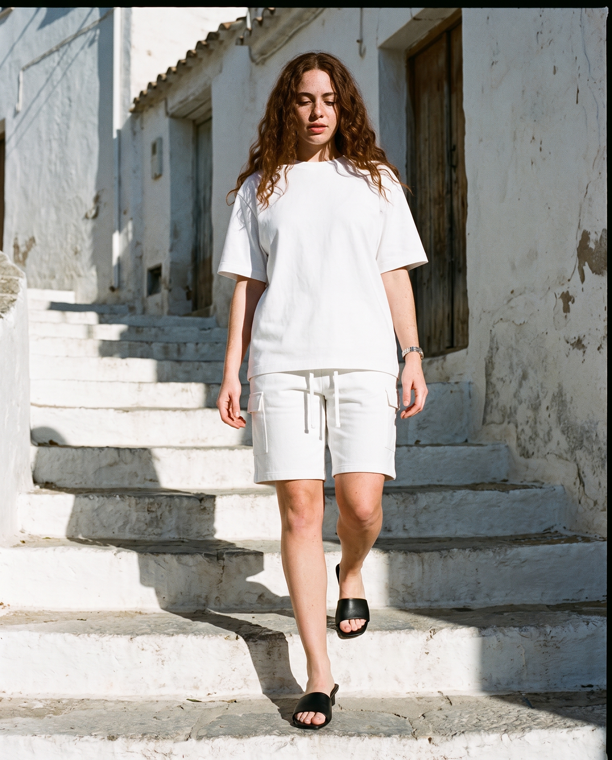 Woman in White drawstring cargo shorts and a white oversized T-shirt, walking down whitewashed steps