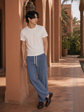 Marcel Afters Drawstring Waist Straight-Leg Cargo Pants in Haze Blue, worn by a man, leaning against a terracotta arcade in a white tee