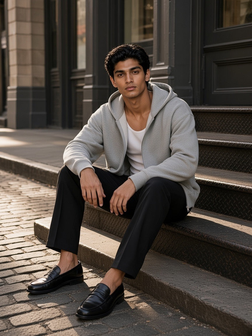Man in the Drop Shoulder Full Zip Hoodie in Flower Gray sitting on steps on a cast-iron street in SoHo, New York in the morning