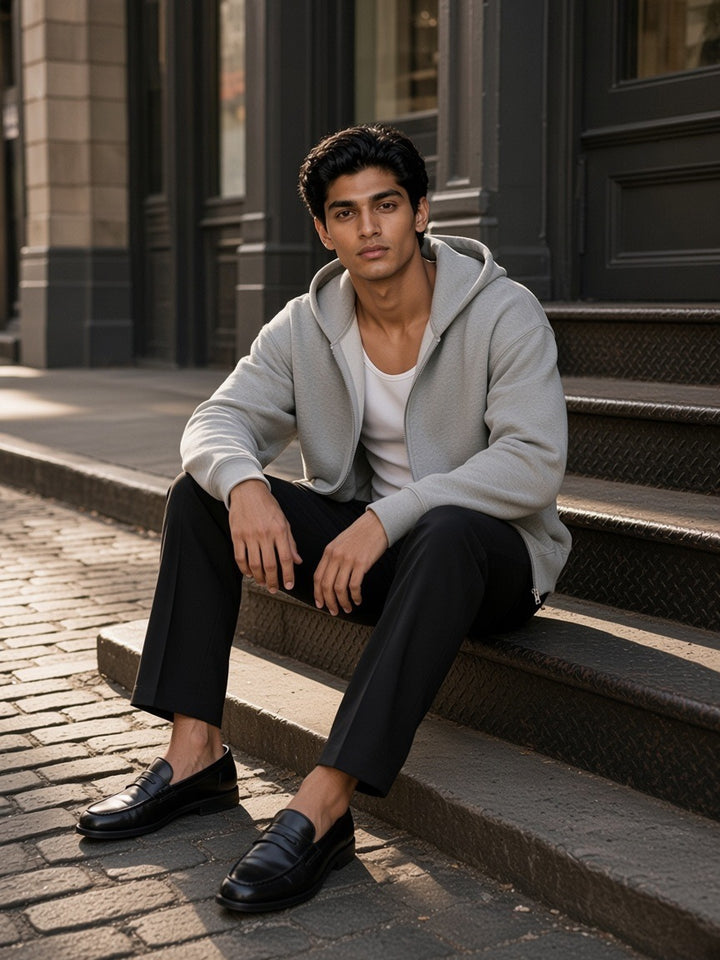 Man in the Drop Shoulder Full Zip Hoodie in Flower Gray sitting on steps on a cast-iron street in SoHo, New York in the morning