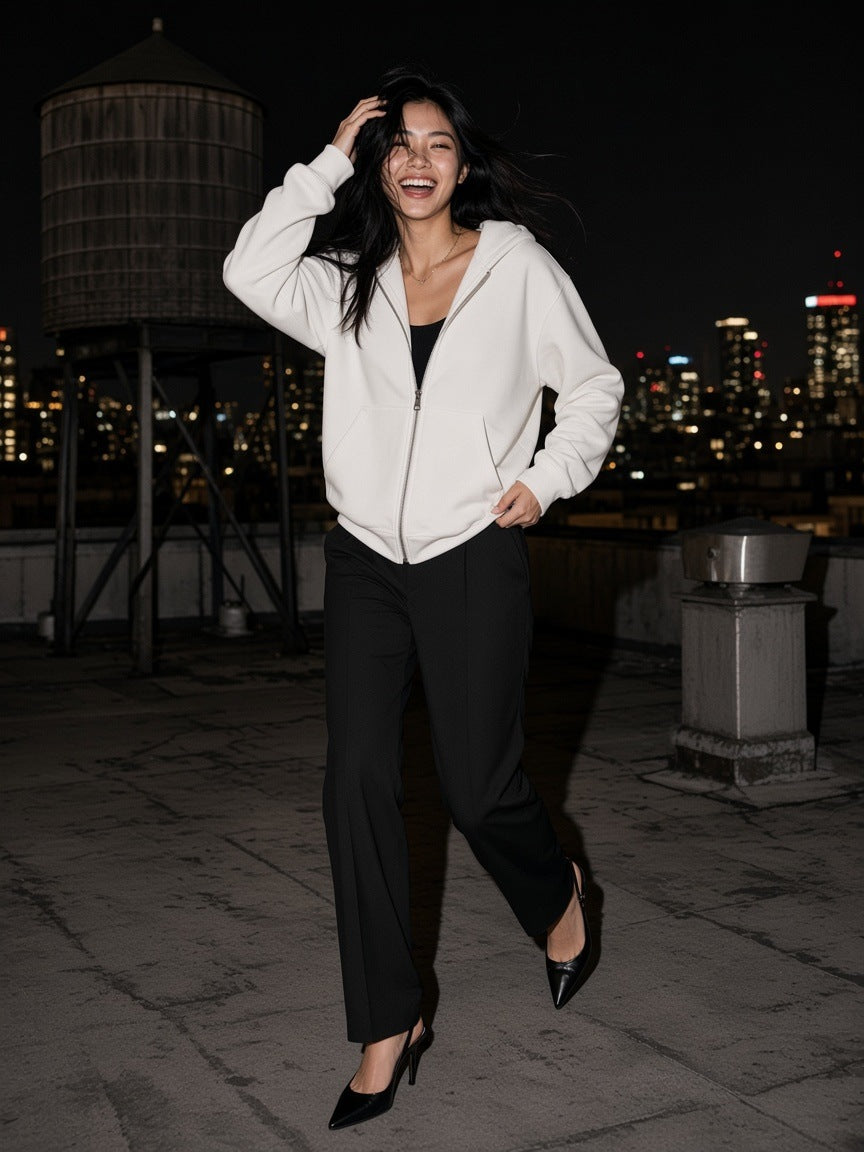 Woman in the Drop Shoulder Full Zip Hoodie in White laughing on a city rooftop at night in flash