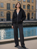 Marcel Afters Drop-Shoulder Zip Up Hoodie in Black, worn by a woman, city canal