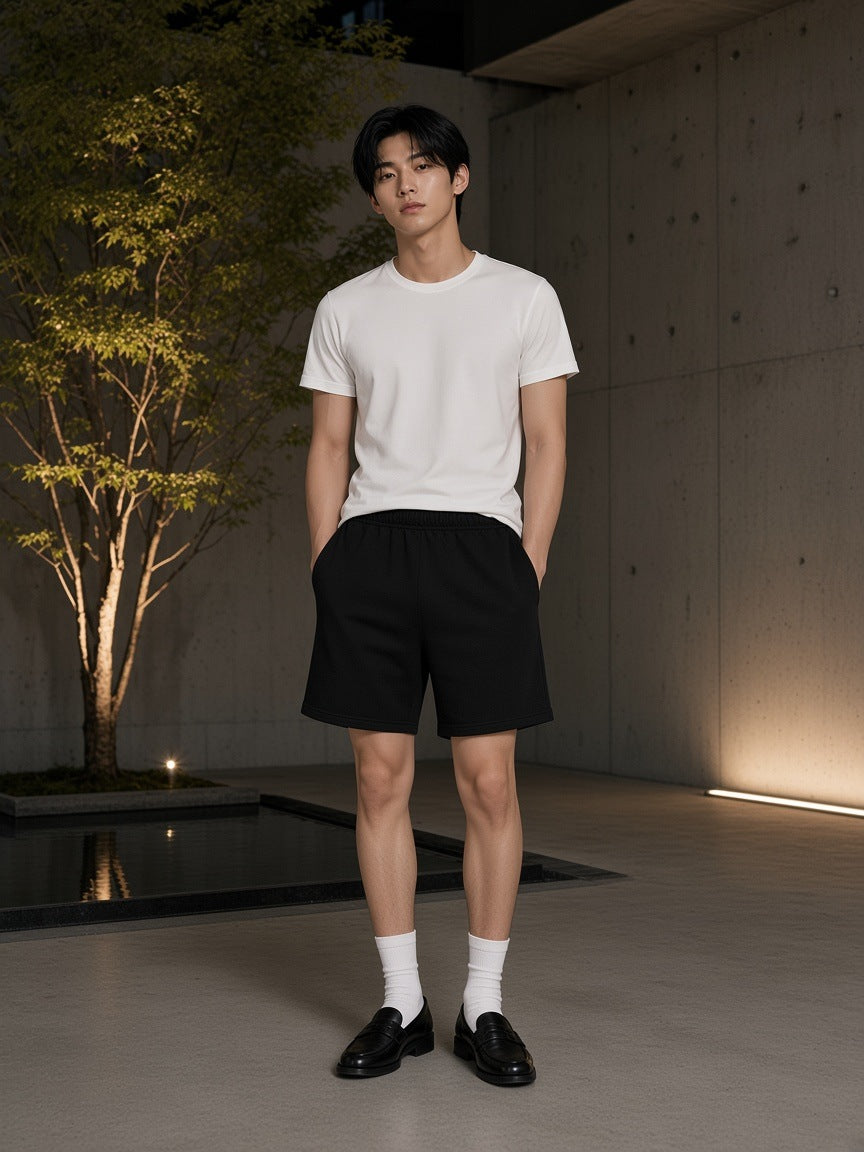 Marcel Afters Earth Tone Loose Fit Cotton Shorts in Black, worn by a man, concrete