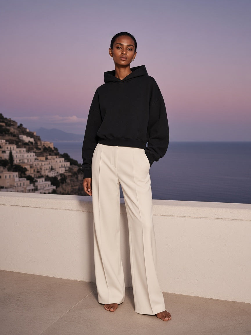 Marcel Afters Essential Boxy Darted Sleeve Hoodie in Black, worn by a woman, on a city rooftop at dusk