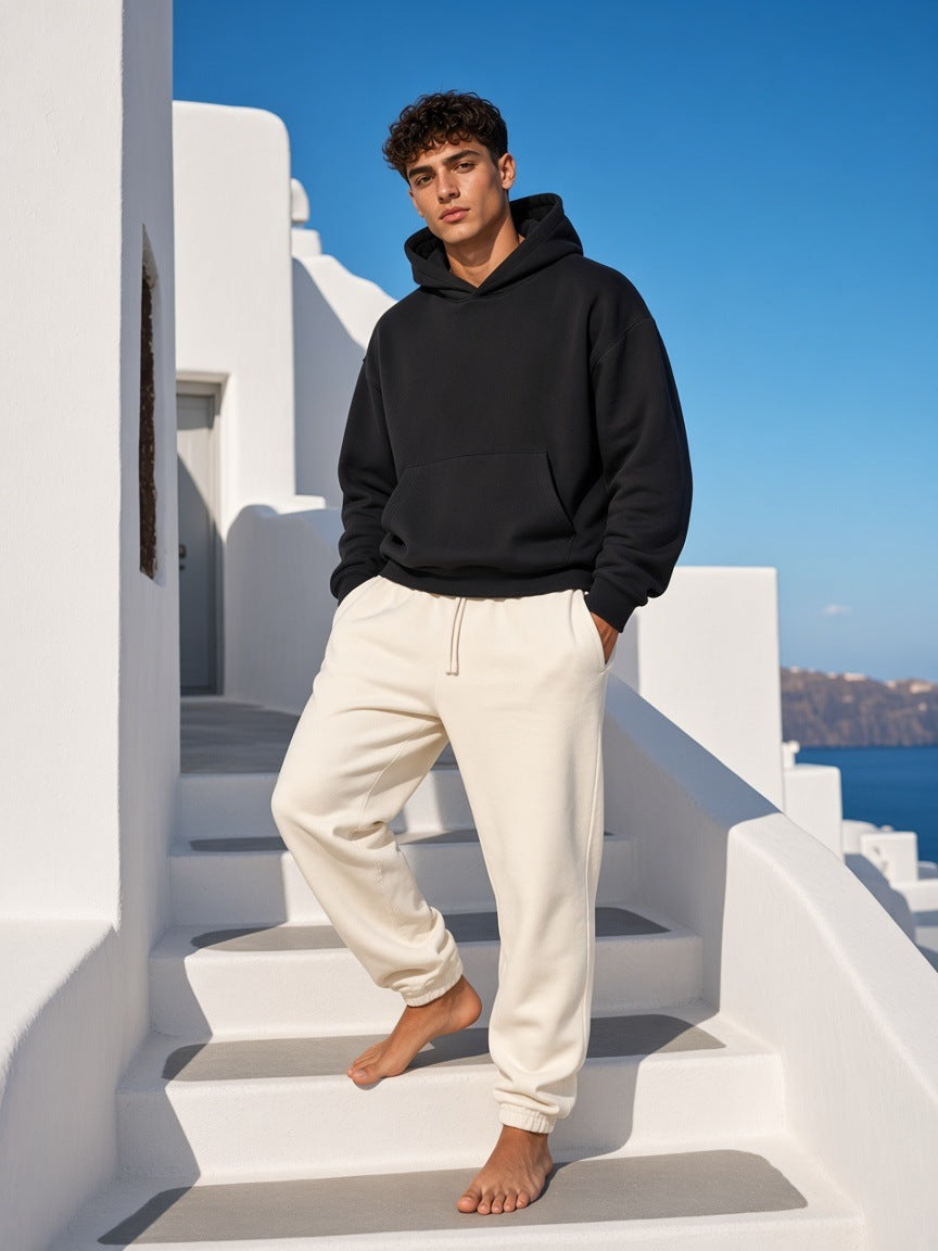 Marcel Afters Essential Boxy Darted Sleeve Hoodie in Black, worn by a man, white building