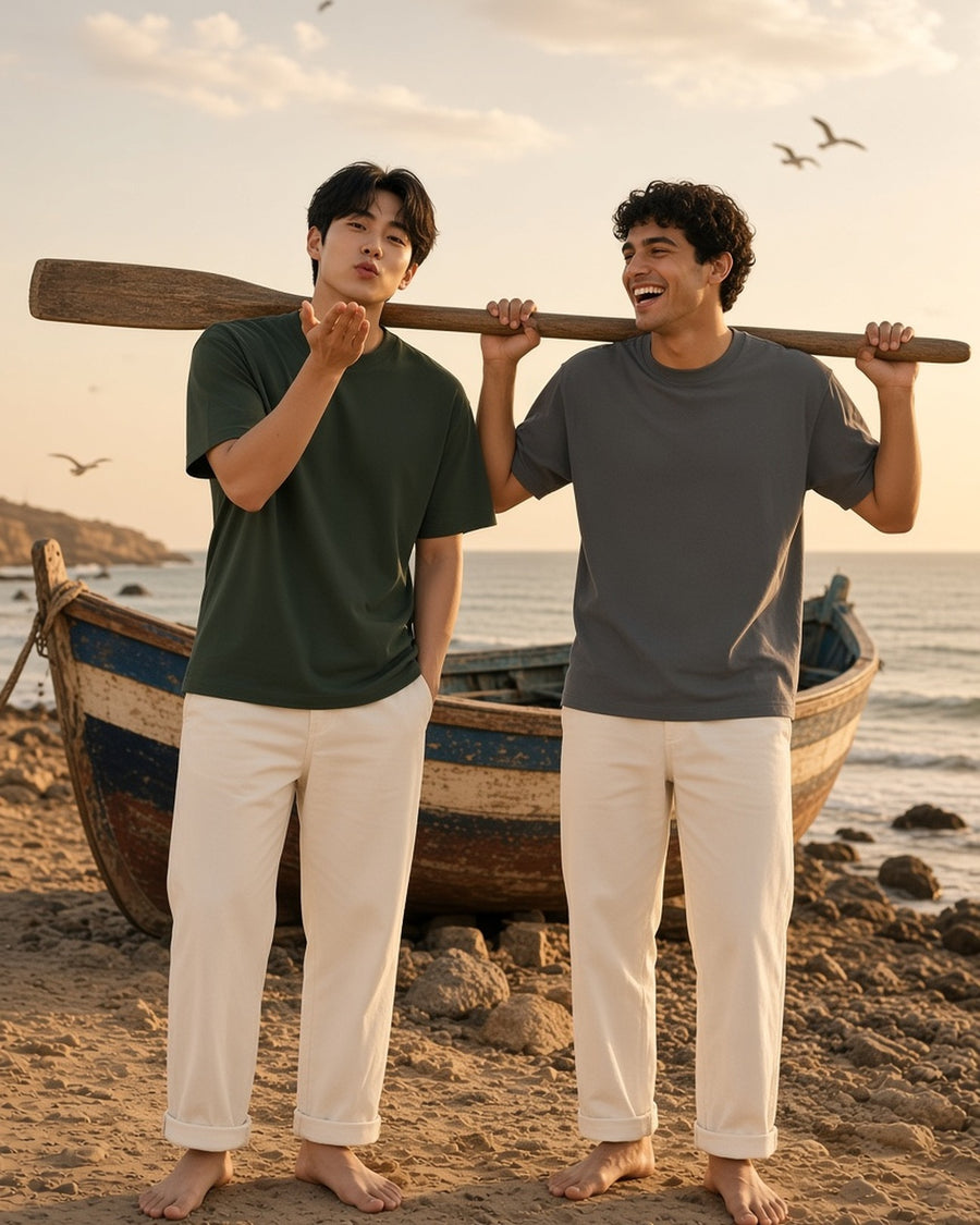 Two men in the Essential Cotton Boxy T-Shirt in Dark Green and Medium Gray carrying an oar on an Atlantic beach