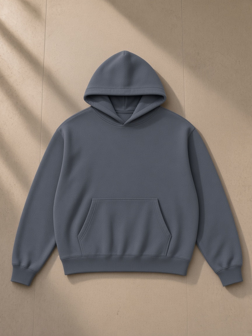 Unisex heavyweight boxy fleece hoodie in Gray Blue, laid flat on pale limestone, front view